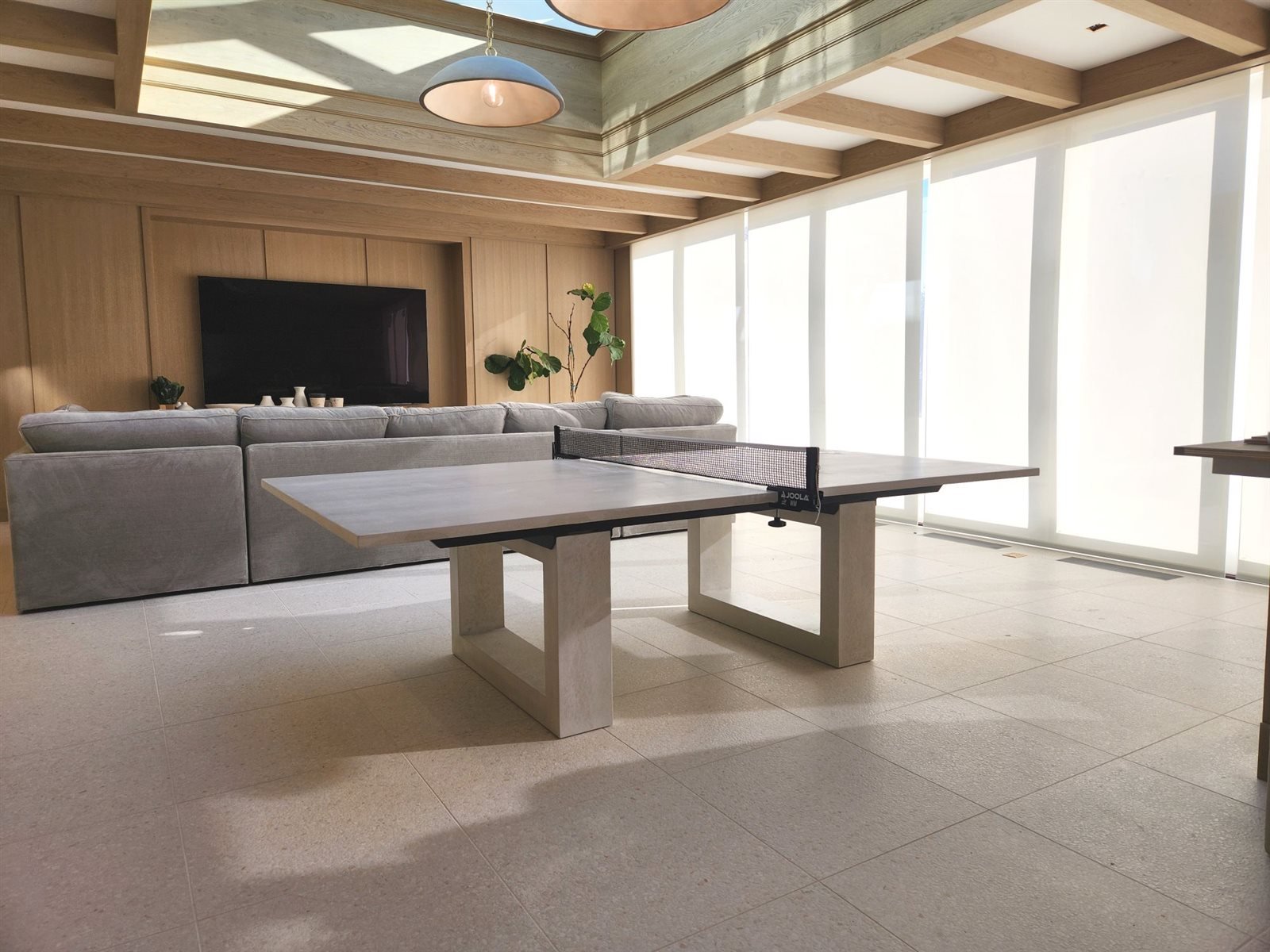 Hand-cast concrete ping pong table in a wood-beamed game room